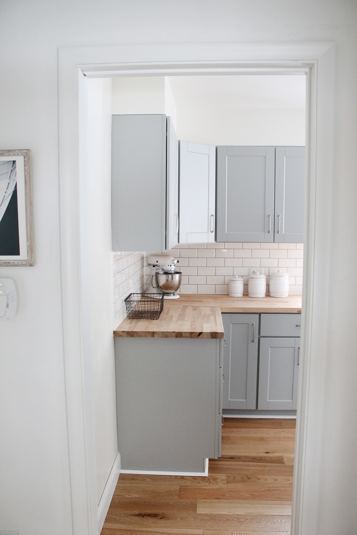 Our small kitchen remodel reveal on a budget with grey cabinets, oak wood flooring, stainless steel appliances, a farmhouse sink and more. Click to see the before and afters. You won't believe what it looked like before!