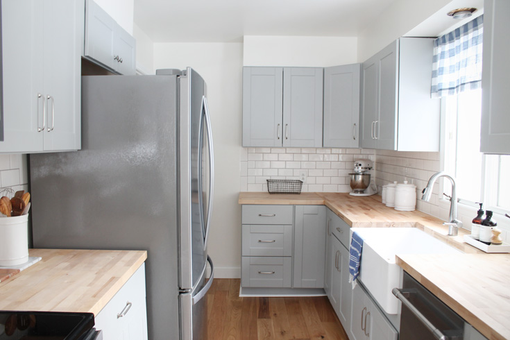 Our small kitchen remodel reveal on a budget with grey cabinets, oak wood flooring, stainless steel appliances, a farmhouse sink and more. Click to see the before and afters. You won't believe what it looked like before!
